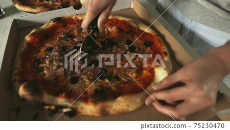 Delicious pizza being sliced up on the table 75230470