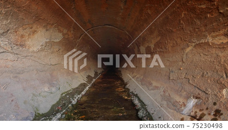 Large sewage tunnel with filth flowing out 75230498