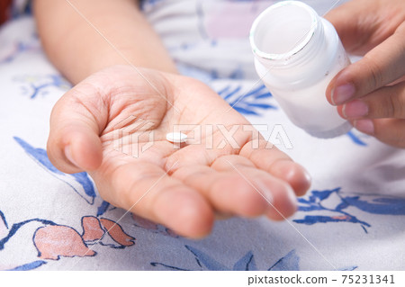 Close up of women hand taking pills Close up of women hand taking pills 75231341