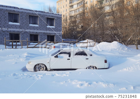 Snow-covered white car with low ground clearance Snow-covered white car with low ground clearance 75231848