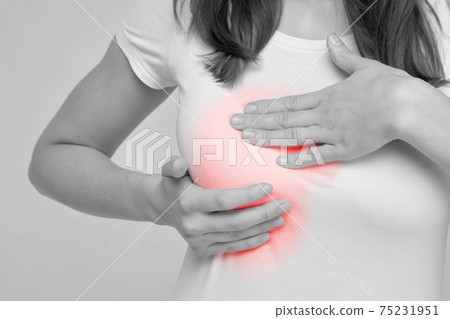 The woman is massaging her breasts because of the feeling of pain. 75231951