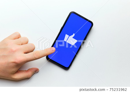 Person hand wants to press the thumb up for evaluation on the Internet using a smartphone Person hand wants to press the thumb up for evaluation on the Internet using a smartphone 75231962