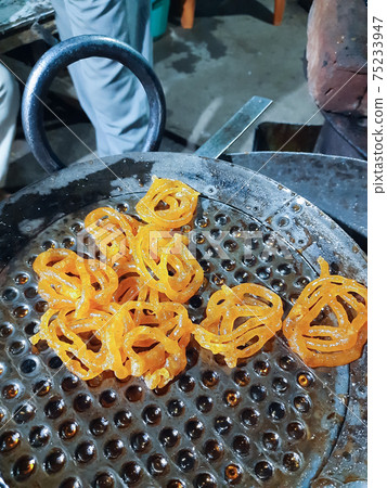 Jalebi is a famous indian sweet. This shows how jalebi are 1st fried in oil 75233947