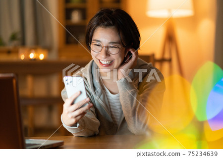 一個年輕的女人在晚上在客廳裡在她的智能手機上進行變焦對話 75234639