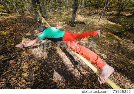 Portrait of a mature male highliner doing slackline balance training in the forest in autumn Portrait of a mature male highliner doing slackline balance training in the forest in autumn 75236235