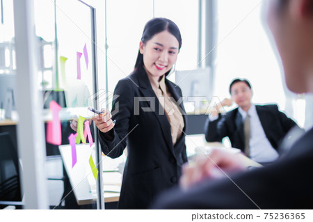 asia business man and woman pointing to paper post it on glass board explain document with manager in the office.businesswoman in meeting with colleagues, gesturing.Selective Focus asia business man and woman pointing to paper post it on glass board explain document with manager in the office.businesswoman in meeting with colleagues, gesturing.Selective Focus 75236365