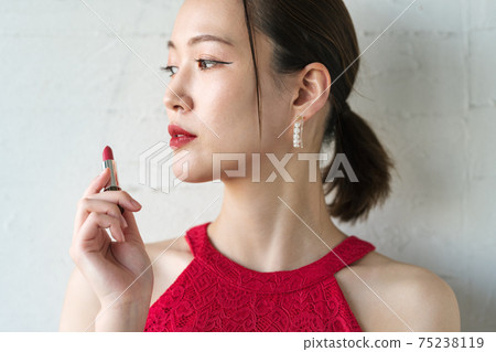 Woman applying bright red lipstick Woman applying bright red lipstick 75238119