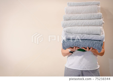 Woman holding a stack of towels 75238344