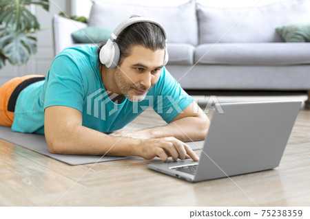 Close-up view of a middle-aged man making an online video call to his coach. He's getting ready for an online workout. 75238359