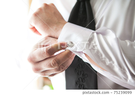 The groom wears an shirt with cufflinks in the morning. The groom wears an shirt with cufflinks in the morning. 75239099