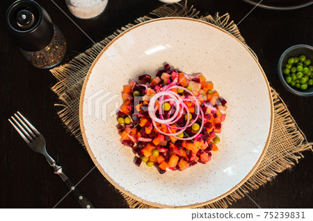 Vinaigrette. Traditional russian beetroot salad with boiled vegetables, pickled cucumbers, sour cabbage, olive oil and green canned peas. Vegetarian healthy dinner. Served in restaraunt. 75239831