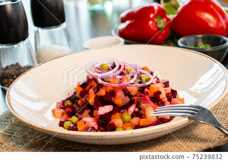 Vinaigrette. Traditional russian beetroot salad with boiled vegetables, pickled cucumbers, sour cabbage, olive oil and green canned peas. Vegetarian healthy dinner. Served in restaraunt. 75239832