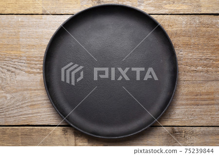 Empty cast iron frying pan on wooden culinary background. Space for text. Empty cast iron frying pan on wooden culinary background. Space for text. 75239844
