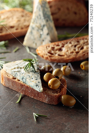 Blue cheese with green olives, rosemary, and bread. Blue cheese with green olives, rosemary, and bread. 75240239