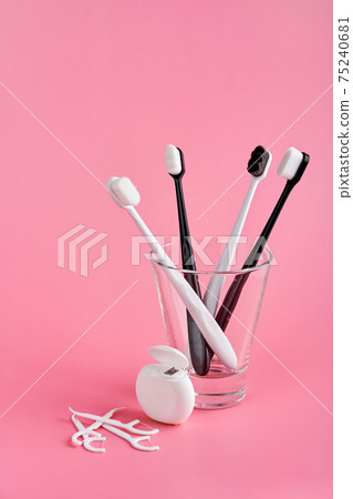 Fashionable toothbrush with soft bristles. Popular toothbrushes. Hygiene trends. Oral hygiene kit. Toothbrushes in glass, floss thread and toothpicks on a pink background Fashionable toothbrush with soft bristles. Popular toothbrushes. Hygiene trends. Oral hygiene kit. Toothbrushes in glass, floss thread and toothpicks on a pink background 75240681