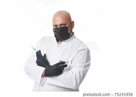 Mature doctor in a medical mask and protective gloves holds syringes with a medicine or vaccine in crossed hands. Portrait isolated on white with copy space. Mature doctor in a medical mask and protective gloves holds syringes with a medicine or vaccine in crossed hands. Portrait isolated on white with copy space. 75241936