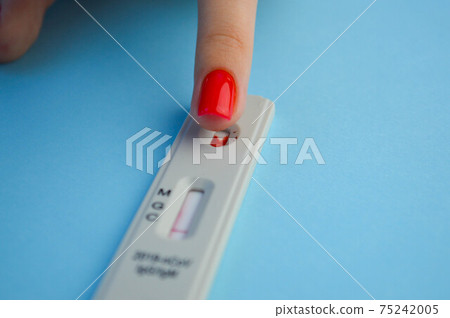test for coronavirus on a blue background. a girl with a bright red manicure makes a blood test to determine the IgG and IgM class antibodies. health monitoring 75242005