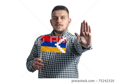 White guy holding a flag of Nagorno-Karabakh Republic and with a serious face shows a hand stop sign isolated on a white background 75242320