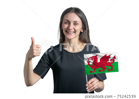 Happy young white woman holding flag of Wales and shows the class by hand isolated on a white background 75242539