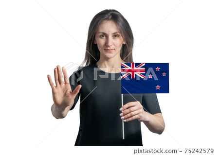 Happy young white woman holding flag of New Zealand and with a serious face shows a hand stop sign isolated on a white background Happy young white woman holding flag of New Zealand and with a serious face shows a hand stop sign isolated on a white background 75242579