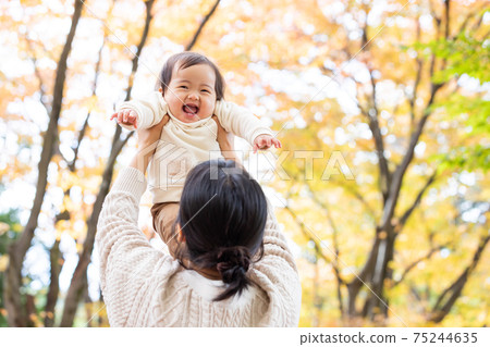 Baby playing with mom in autumn park 75244635