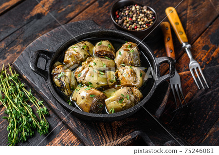 Marinated artichokes in olive oil in a pan. Dark wooden background. Top view Marinated artichokes in olive oil in a pan. Dark wooden background. Top view 75246081