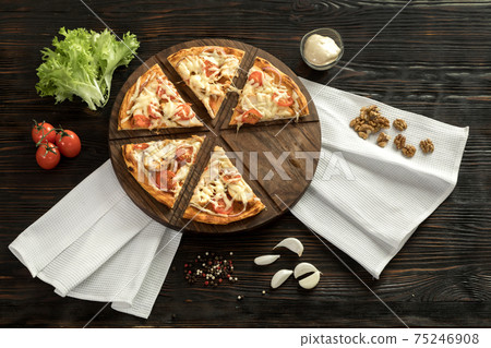 Delicious pizza on a wooden cutting board Delicious pizza on a wooden cutting board 75246908