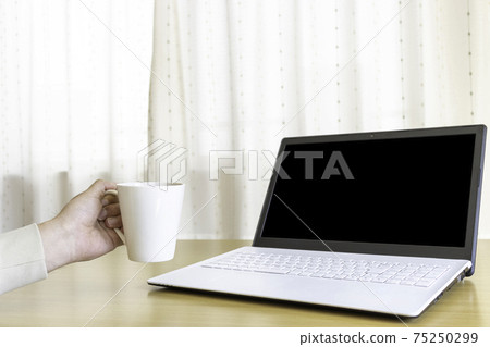 A man pointing a coffee cup at a laptop 75250299