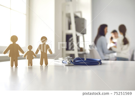 Stethoscope and small wooden family member figures on doctor's table at the hospital 75251569