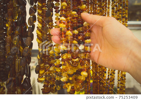 Vintage photo, Hand of woman with shiny womanly amber necklaces on stall Vintage photo, Hand of woman with shiny womanly amber necklaces on stall 75253409