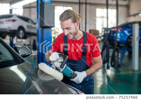 Responsible man polishing car in workshop. 75257466