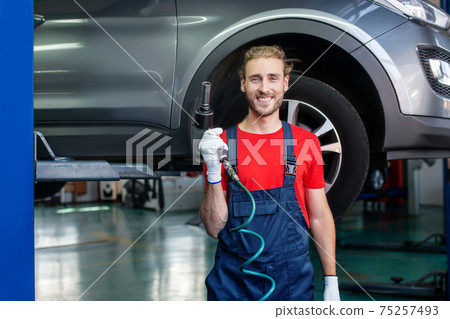 Happy man with work tool in garage 75257493