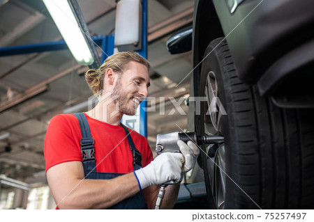 Satisfied man near wheel of car being repaired Satisfied man near wheel of car being repaired 75257497