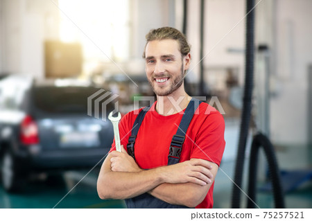 Joyful man motor mechanic standing in workshop Joyful man motor mechanic standing in workshop 75257521