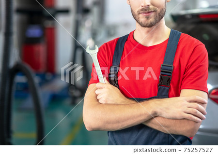 Professional car workshop worker with wrench 75257527
