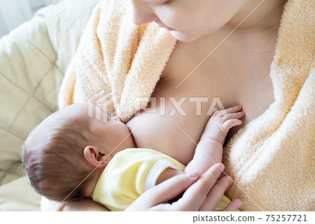 Baby eating breast milk. Caucasian blonde young mother breastfeeding her baby horizontal photo. Concept of lactation. Baby eating breast milk. Caucasian blonde young mother breastfeeding her baby horizontal photo. Concept of lactation. 75257721