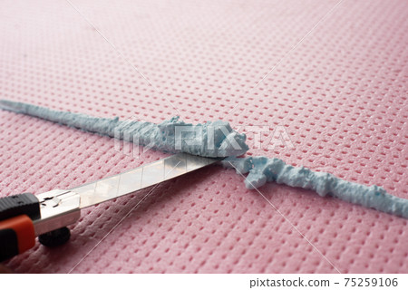 the master with a knife cuts off excess construction foam 75259106