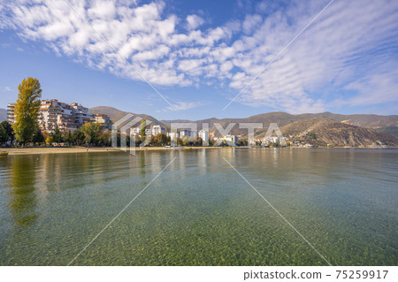 Amazing view on the green tree, mountains, sea with turquoise water and colorful blue sky at sunrise. Summer landscape in mountains on seashore. 75259917