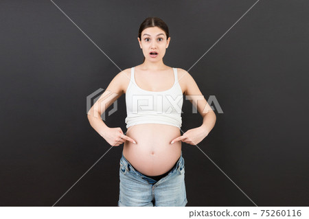 Picture of shocked or surprised pregnant lady standing over colored background. Looking at camera Picture of shocked or surprised pregnant lady standing over colored background. Looking at camera 75260116