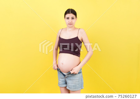 pregnant woman in unzipped jeans showing her naked belly at colorful background with copy space. Baby expecting concept pregnant woman in unzipped jeans showing her naked belly at colorful background with copy space. Baby expecting concept 75260127