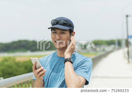 A man listening to music while jogging 75260233