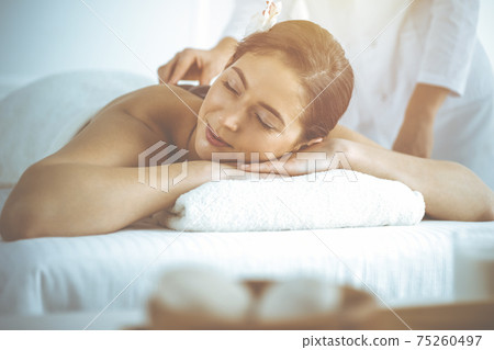 Beautiful brunette woman enjoying back massage with closed eyes. Spa and medicine concept Beautiful brunette woman enjoying back massage with closed eyes. Spa and medicine concept 75260497