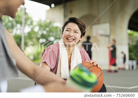 Men and women taking a break while practicing basketball Men and women taking a break while practicing basketball 75260600