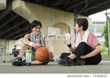 Men and women taking a break while practicing basketball 75260622