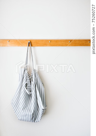 Minimalistic neutral tones mockup with organic cotton eco tote shopper bag on wooden hanger on a gray wall. Zero waste, Sustainable lifestyle, ecology concept Minimalistic neutral tones mockup with organic cotton eco tote shopper bag on wooden hanger on a gray wall. Zero waste, Sustainable lifestyle, ecology concept 75260727