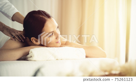 Pretty brunette woman enjoying procedure of back massage in spa salon. Beauty concept Pretty brunette woman enjoying procedure of back massage in spa salon. Beauty concept 75261123