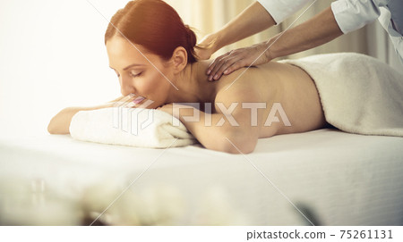 Pretty brunette woman enjoying procedure of back massage in spa salon. Beauty concept Pretty brunette woman enjoying procedure of back massage in spa salon. Beauty concept 75261131