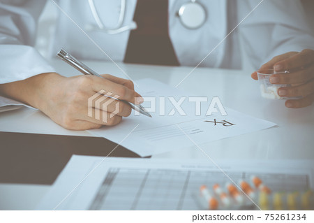 Unknown woman-doctor fills up prescription form. close-up. Panacea and life save, prescribe treatment, legal drug store. Medicine concept Unknown woman-doctor fills up prescription form. close-up. Panacea and life save, prescribe treatment, legal drug store. Medicine concept 75261234