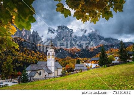 Cute alpine village with traditional mountain church, Dolomites, Colfosco, Italy  75261622