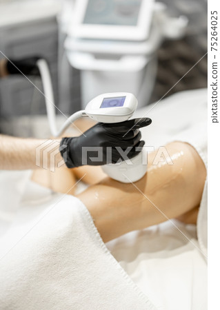 Doctor doing ultrasound liposuction procedure in medical clinic. 75264025